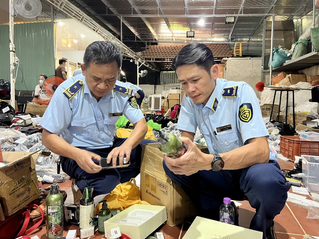 Lực lượng chức năng ghi nhận hàng hóa được chất đống ngổn ngang mang thương hiệu nổi tiếng từ khu vực phía ngoài cổng đến kho chứa sâu bên hông khu vực nhà ở. Ảnh TCQLTT